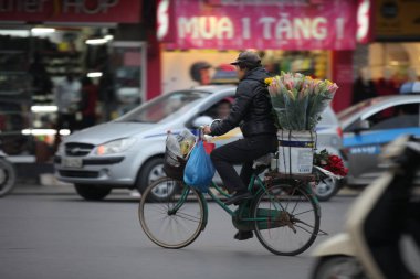 Hanoi başkenti, Vietnam - 12 Temmuz 2019 Hanoi, Vietnam 'daki sokak satıcıları. Taşralı kadın işlek bir sokakta taze çiçek satıyor.