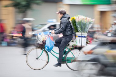 Hanoi başkenti, Vietnam - 12 Temmuz 2019 Hanoi, Vietnam 'daki sokak satıcıları. Taşralı kadın işlek bir sokakta taze çiçek satıyor.
