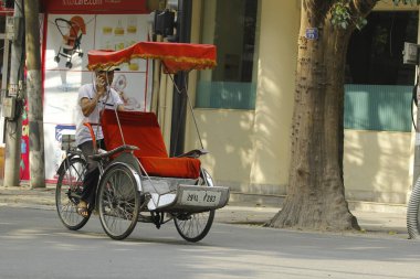 Hanoi, Vietnam - 16 Ekim 2016. Geleneksel bisikletçi, Hanoi, Vietnam sokaklarında yolcu beklerken sigara molası veriyor. Bisiklet üç tekerli bir taksidir..