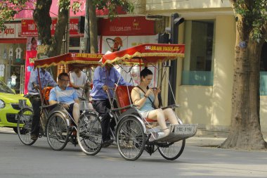 Hanoi, Vietnam - 16 Ekim 2016. Geleneksel bisikletçi, Hanoi, Vietnam sokaklarında yolcu beklerken sigara molası veriyor. Bisiklet üç tekerli bir taksidir..