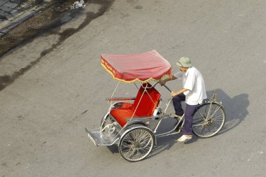 Hanoi, Vietnam - 16 Ekim 2016. Geleneksel bisikletçi, Hanoi, Vietnam sokaklarında yolcu beklerken sigara molası veriyor. Bisiklet üç tekerli bir taksidir..