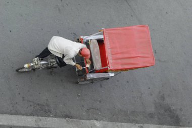 Hanoi, Vietnam - 16 Ekim 2016. Geleneksel bisikletçi, Hanoi, Vietnam sokaklarında yolcu beklerken sigara molası veriyor. Bisiklet üç tekerli bir taksidir..