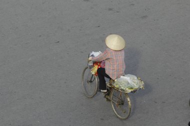 Hanoi, Vietnam - 15 Ekim 2016. Hanoi, Vietnam sokaklarında bisikletli bir sokak satıcısı. Başkentteki yoğun trafiğin ortasında geleneksel şapkalar satmak.