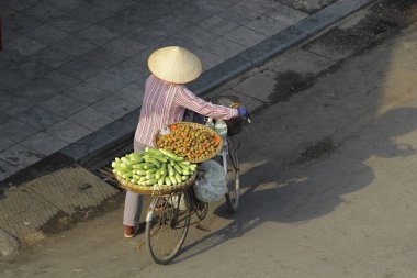 Hanoi, Vietnam - 15 Ekim 2016. Hanoi, Vietnam sokaklarında bisikletli bir sokak satıcısı. Başkentteki yoğun trafiğin ortasında geleneksel şapkalar satmak.