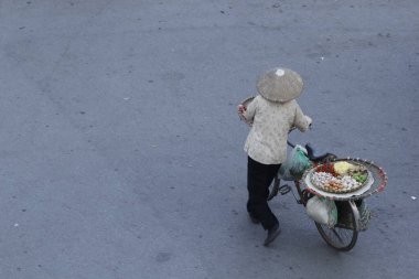 Hanoi, Vietnam - 15 Ekim 2016. Hanoi, Vietnam sokaklarında bisikletli bir sokak satıcısı. Başkentteki yoğun trafiğin ortasında geleneksel şapkalar satmak.