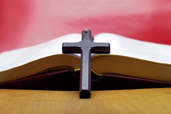 Black wooden cross  on bible book. Pray and service to the god.