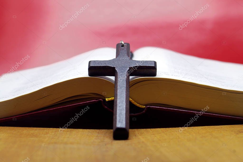 Black wooden cross  on bible book. Pray and service to the god.