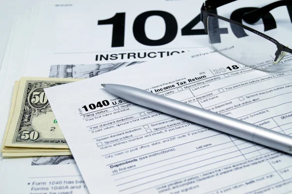 Income tax form with instruction, glasses and pen.