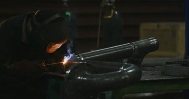 Kaynakçı Kaynak maskesi, iş giyisi fabrikada, fabrika odasında boru kaynak. Kaynakçı. Sanayi. Fabrikada çalışmak. Boru kaynak. Elektrot. Erime. Kaynak çalışır. Ağır çekim. Grubu.