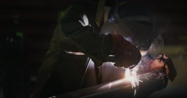 Kaynakçı Kaynak maskesi, iş giyisi fabrikada, fabrika odasında boru kaynak. Kaynakçı. Sanayi. Fabrikada çalışmak. Boru kaynak. Elektrot. Erime. Kaynak çalışır. Ağır çekim. Grubu.