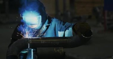 Kaynakçı Kaynak maskesi, iş giyisi fabrikada, fabrika odasında boru kaynak. Kaynakçı. Sanayi. Fabrikada çalışmak. Boru kaynak. Erime. Kaynak çalışır. Sparks. İnsanlarla. Ağır çekim. Bir boru Kaynakçı Kaynak