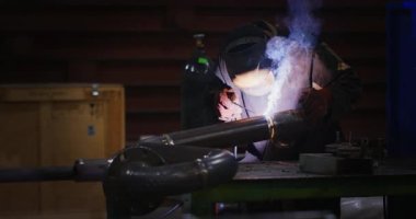 Kaynakçı Kaynak maskesi, iş giyisi fabrikada, fabrika odasında boru kaynak. Kaynakçı. Sanayi. Fabrikada çalışmak. Boru kaynak. Elektrot. Erime. Ağır çekim. Kaynakçı bir boru kaynak. Sparks. Grubu.