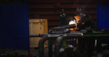 Kaynakçı. Sanayi. Fabrikada çalışmak. Boru kaynak. Electrode.Sparks. kaynak işleri. Yarı otomatik kaynak. Gaz kaynak. Ağır çekim. Kaynakçı Kaynak maskesi, iş giyisi fabrikada, fabrika odasında boru kaynak. . Grubu.