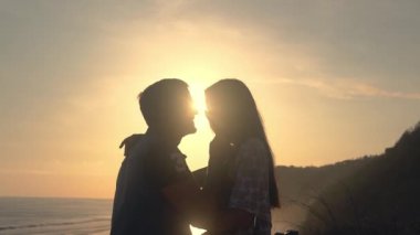 Çift dalga geçmeyi ve karşı günbatımı öpüşme bir motosiklet üzerinde aşık