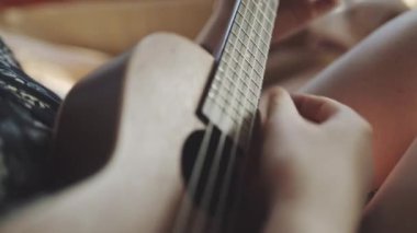 Genç bir kadın arabanın içinde ukulele çalıyor.