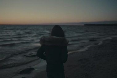 Gün batımı kasvetli plajda yürüyen üzgün kız