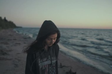 Gün doğumu kasvetli plajda yürüyen üzgün kız