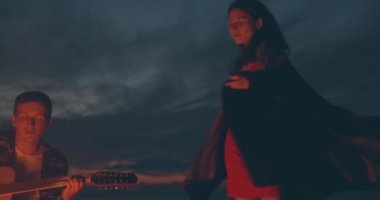 Pretty Man gitar ve kız şenlik ateşi yakınında dans oynuyor