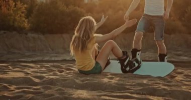 kızlar gün batımında kum tahtası üzerinde ayağa kalkmak için adam yardım