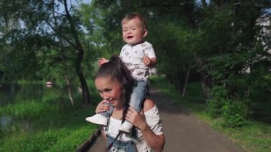 Güzel anne ve tatlı oğlu güzel göletin yanındaki parkta yürüyorlar. Annesinin omuzlarında oturup dünyayı keşfeden tatlı bir çocuk. Annelik kavramı, mutluluk, aşk.