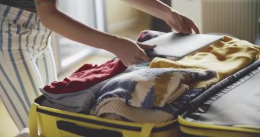 Yakın plan. Kız seyahatte bavul topluyor. Taşınma, tatil, tatil, tatil kavramı. Güzel güneşli bir gün. Kameranın lensine güneş ışığı düştü. 12 bitlik renklerle bir film kamerasında çekildi..