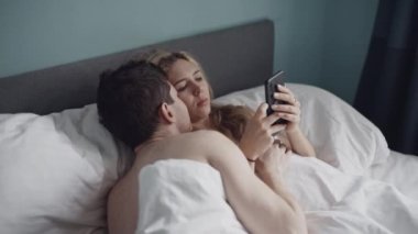 Heteroseksüel çift yatakta sorun yaşıyor. Kadının telefon bağımlılığı var ve erkek arkadaşına tazminat ödemiyor. Evlilik, telefon bağımlılığı, aile, aşk, seks konsepti. Çekimler kırmızı 4k, 10 bit renk