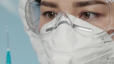 Laboratuvarda yüz maskesi takan ve koruyucu gözlük takan bir doktorun portresi. Kadın cerrah gözlerini kapat. Covid-19, virüs, koronavirüs, salgın, izolasyon, tıbbi konsept.