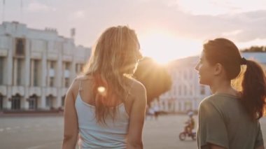 Gençlik kavramı, aktif yaşam ve gençlik ruhu. İki mutlu bayan arkadaş gün batımında birlikte kaykay yaparak vakit geçiriyorlar. Güzel melez kızlar eğleniyor. Spor ve arkadaşlık yaşam tarzı..