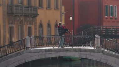 Yakışıklı bir adam, balayı sırasında Venedik köprüsünde duran Asyalı sevgilisini öpüyor ve sarılıyor. Tatili geçirmenin en iyi yolu Avrupa 'ya seyahat etmek..