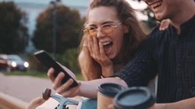 Akıllı telefondan bir şey izlerken gülen mutlu öğrenci arkadaşlar. Üç tane çok ırklı genç insan dışarıda birlikte vakit geçiriyor. Arkadaşlık, iletişim, gençlik ve yaşam tarzı kavramı