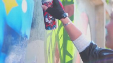 Güzel genç kız yazın şehir duvarına sprey boyayla renkli bir grafiti yapıyor. Yaratıcı sanat. Yetenekli yeniyetme kız öğrenci resim çiziyor. Özgürlük, yaşam tarzı, kültür kavramı.