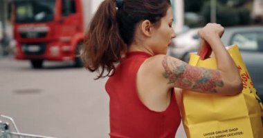 Kadın, arabadan arabaya ürünler yüklüyor. Süpermarketten almak. Gir, dükkândan aldığı çantalarla park yerinde duruyordu. Yalnız başına oldukça Asyalı alışverişi. Satın alma ve satma kavramı, ticaret endüstrisi