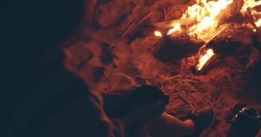 Solo aktivite ve sosyal uzaklık. Yalnız kız, ormanın yakınındaki sahilde şenlik ateşinde oturmuş çay ya da kahve içiyor. Yalnızlıktan zevk alan bir kadın. Yaz tatili kavramı. Doğada boş zaman geçir.