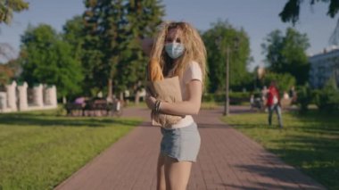 Salgın alışverişi. Karantinadan sonra başka bir hayata alışırsın. Koruyucu maskeli ve eldivenli genç mutlu bir kadın dükkandan eve ürünler taşıyor. Kapsamlı etki konsepti. Yeni gerçeklik.