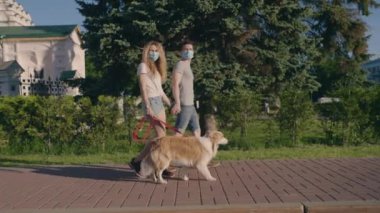 Toplumsal uzaklık. Sevgi dolu bir çift maske takıyor ve şehir parkında bir çoban köpeğiyle yürüyor. Sıcak havanın tadını çıkarıyor. İnsanlar ve hayvanlar konsepti. Keyifli yaz