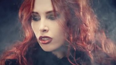 Kızıl saçlı ve şeytan boynuzlu bir cadı portresi. Kadın şeytani bir şekilde gülümsüyor ve büyü yapıyor. Karanlık güçler tarikatı, şeytan çağırma ayinleri, cadılar bayramı, okültizm, ezoterik.