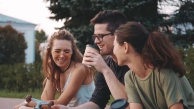 Mutlu gülümseyen genç arkadaşlar dışarıda akıllı telefondan ya da cep telefonundan bir şeye gülüyorlar. Üç tane çok ırklı genç insan birlikte vakit geçiriyor. Arkadaşlık, iletişim, gençlik ve yaşam tarzı kavramı