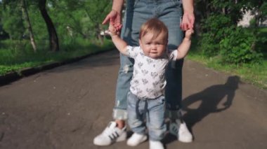 Güzel anne ve küçük oğlu dışarıda. Çocuk annesinin elini tutuyor. Yazın ilk adımlarını atan sevimli bir çocuğun portresi. Güzel anne ve çocuk parkta birlikte oynuyorlar. Annelik kavramı