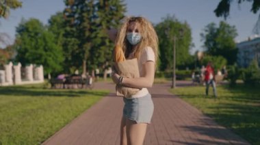 Salgın alışverişi. Karantinadan sonra başka bir hayata alışırsın. Koruyucu maskeli ve eldivenli genç mutlu bir kadın dükkandan eve ürünler taşıyor. Kapsamlı etki konsepti. Yeni gerçeklik.