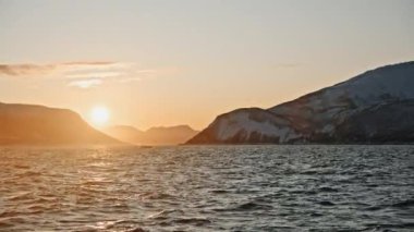 Kuşlar gökyüzünde uçuyor. Sinematik gün batımı. Norveç kutup denizinin karla kaplı fiyortlarla çevrili manzarası. Norveç 'e bilimsel keşif gezisi sırasında çekilen özel belgesel görüntüleri