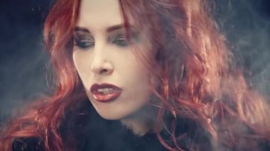 Kızıl saçlı ve şeytan boynuzlu bir cadı portresi. Kadın şeytani bir şekilde gülümsüyor ve büyü yapıyor. Karanlık güçler tarikatı, şeytan çağırma ayinleri, cadılar bayramı, okültizm, ezoterik.