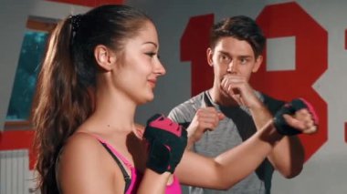 Atletik kız antrenörle tek başına çalışıyor. Genç esmer boksör ve antrenör. Erkek ve kadın kardiyo çalışması yapıyor. Adam kıza antrenman için yardım ediyor. Antrenman, güç, spor salonu kavramı.