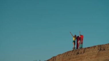 İki güzel kız ellerinde tahtalarla uçurumun kenarında duruyor, başarıyla seviniyor, gülümsüyor ve sarılıyorlar. Çölde tatilde olan genç bayanlar. Dostluk, seyahat, spor kavramı..