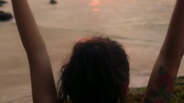 Güzel esmer, okyanus kıyısında meditasyon yapıyor. Kadın elleri altın gün batımının önünde yoga egzersizleri yapıyor. Genç kızın vücudu incedir. Sağlık hayatı kavramı. Meditasyon, rahatlama, özgürlük. mutluluk.