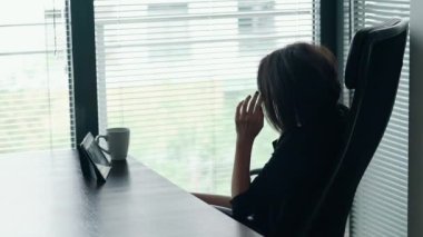 Serbest çalışma kavramı, teknoloji. Ofiste çalışan ve telefonda konuşan genç iş kadınının portresi. Kadın girişimci ciddi bir konuşma yapıyor, durumu çözmeye ve çözüm bulmaya çalışıyor..