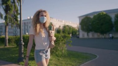 Salgın alışverişi. Salgını önlemek için sosyal mesafe. Karantinadan sonra başka bir hayat. Koruyucu maskeli ve eldivenli genç bir kadın dükkandan eve ürünlerle dolu bir çanta taşıyor. Covid etkisi konsepti.