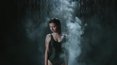 Yağmurun altında siyah arka planda tek başına duran ve elini kaldıran bir kadın. Zihin tamamen sakin. Yüzücü başarısızlık, yalnızlık ve kızgınlığın üstesinden geldi, artık gözyaşı yok.