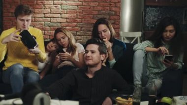 Bir grup genç ev partisinde sıkılıyor. Milenyum kuşakları akıllı telefonlarını, cihazlarını kullanıyor, birbirleriyle etkileşime girmiyorlar. Sosyal etkileşim eksikliği gösteriyor. Sahtecilik, can sıkıntısı, teknoloji kavramı.