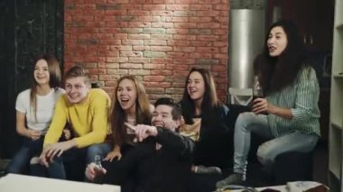 Oturma odasında milenyumlar mutlu ve zaferi sarılarak ve çığlık atarak kutluyorlar. Bir grup genç televizyonda spor müsabakalarını heyecan ve tezahüratla izliyor. Eğlence anlayışı, yaşam tarzı, televizyon..