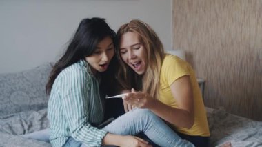 Bebek bekleyen eşcinsel lezbiyen çift. Tüp bebek. Anneliğin mutluluğu, iki kadının pozitif bir teste şaşırması. LGBTQI, Gurur Etkinliği, LGBT Gurur Ayı, ilişki, doğum, konsept.